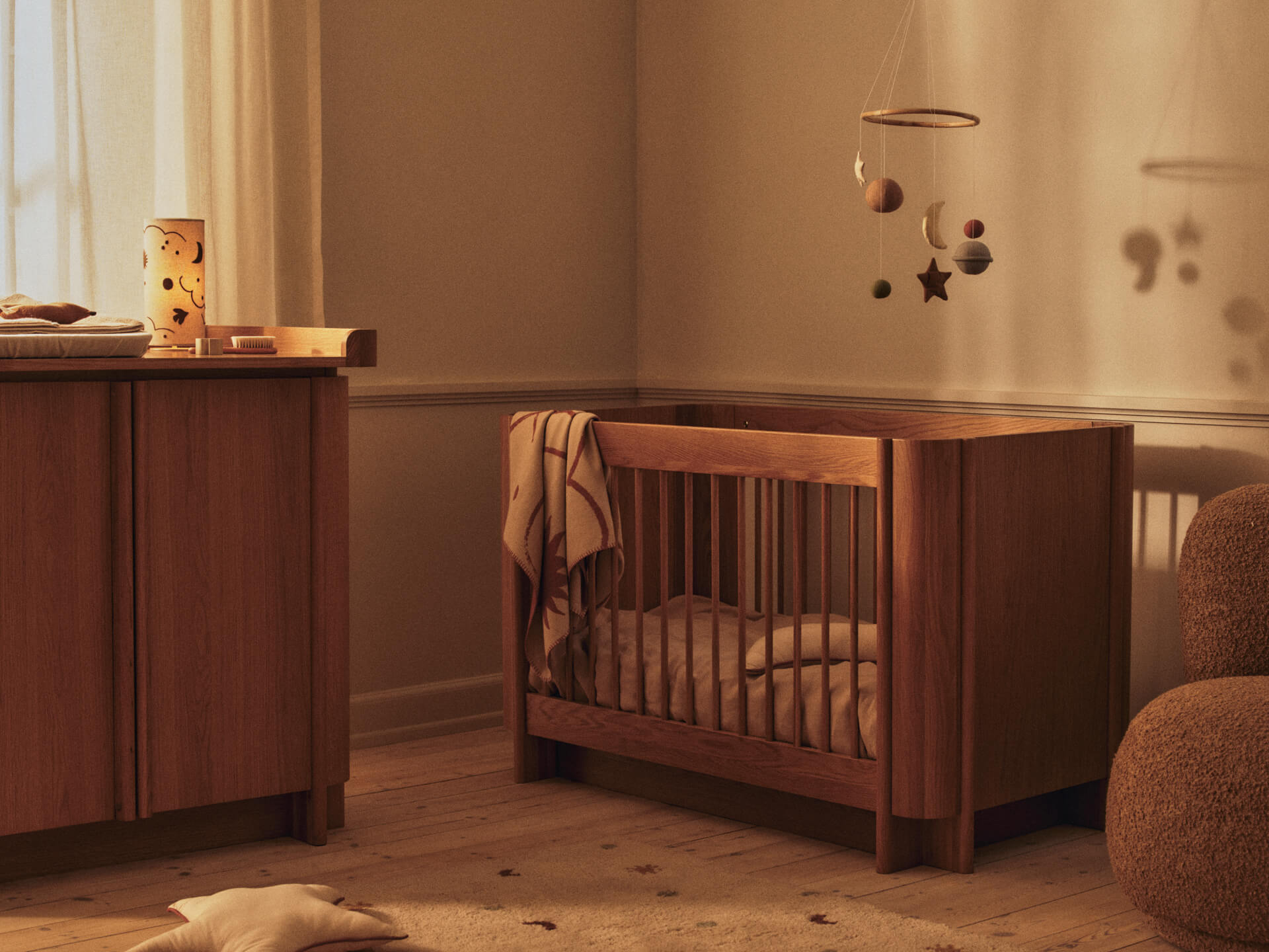 Natural oak Ferm Living baby cot in a soft nursery