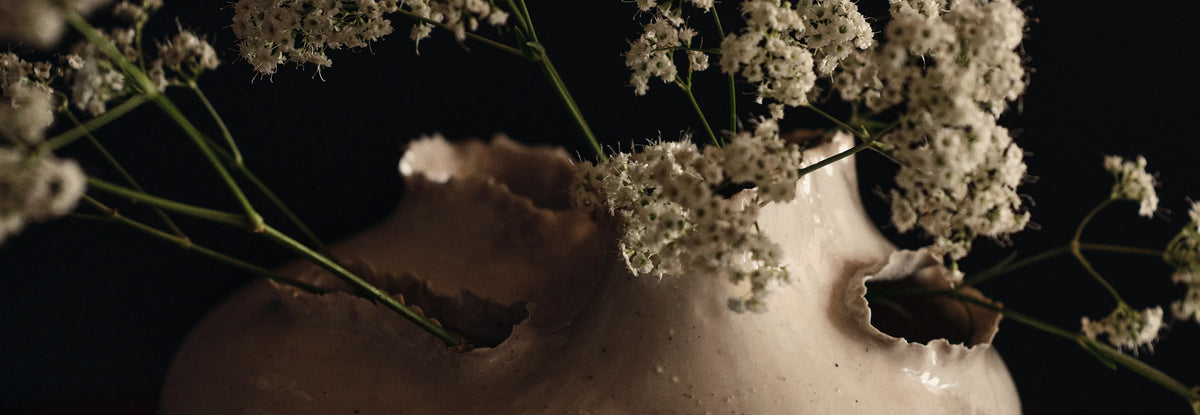 Collection d'accessoires, gros plan d'un vase blanc cassé aux ouvertures déchirées avec des fleurs blanches
